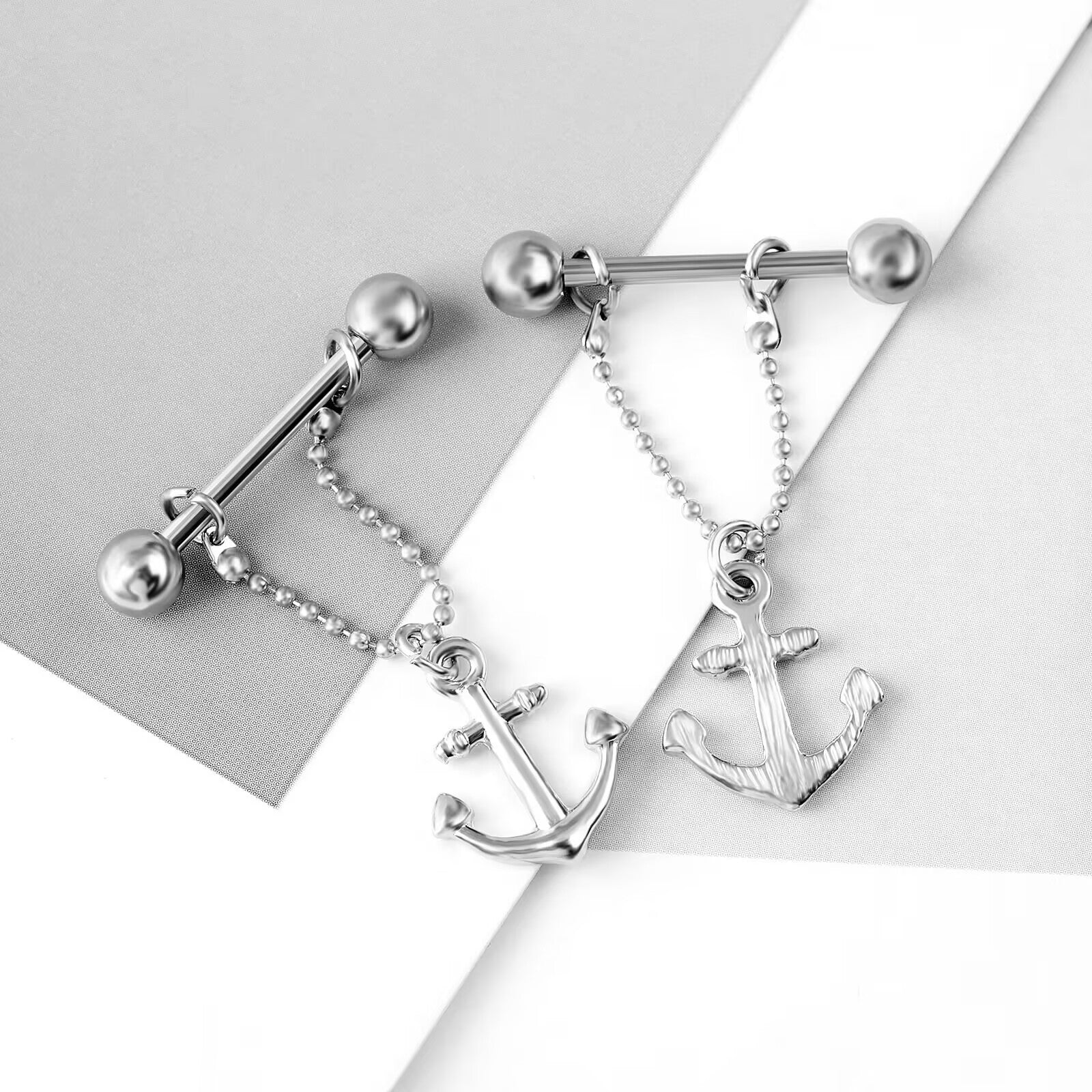 Top-down view of anchor nipple piercings showing high-polish finish