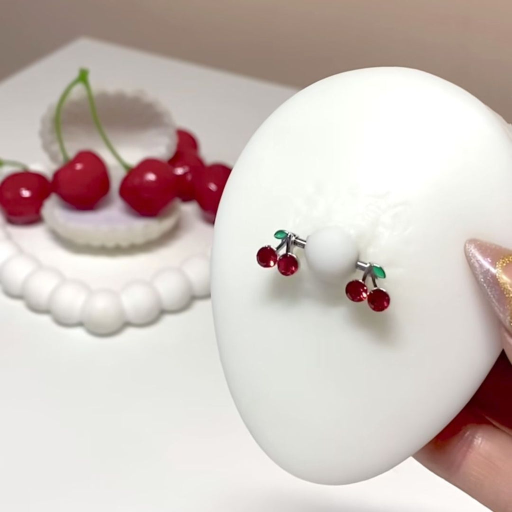 Realistic silicone model wearing a red cherry nipple shield for placement reference.