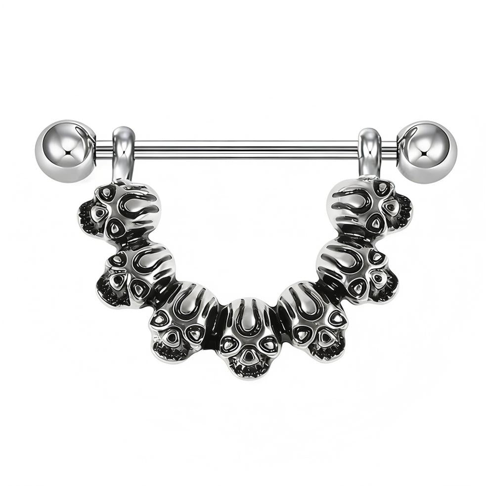 Close-up of a silver-toned nipple shield featuring seven detailed skulls in a semi-circle.