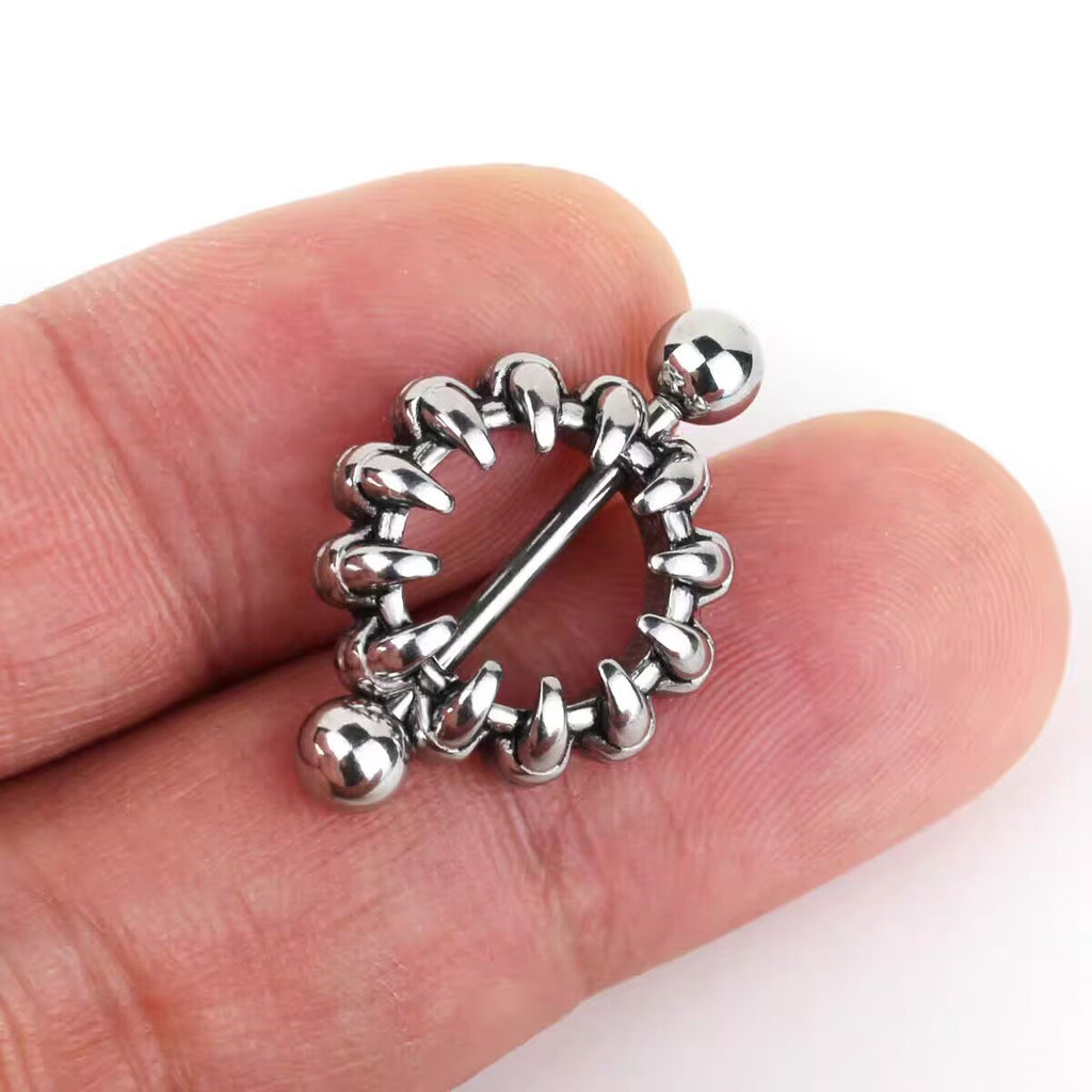 A close-up of a hand holding the claw nipple jewelry, demonstrating its size and how it looks against a skin tone.
