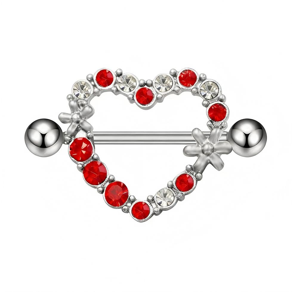 Close-up of a silver heart nipple shield with red and clear crystals and flower charms.