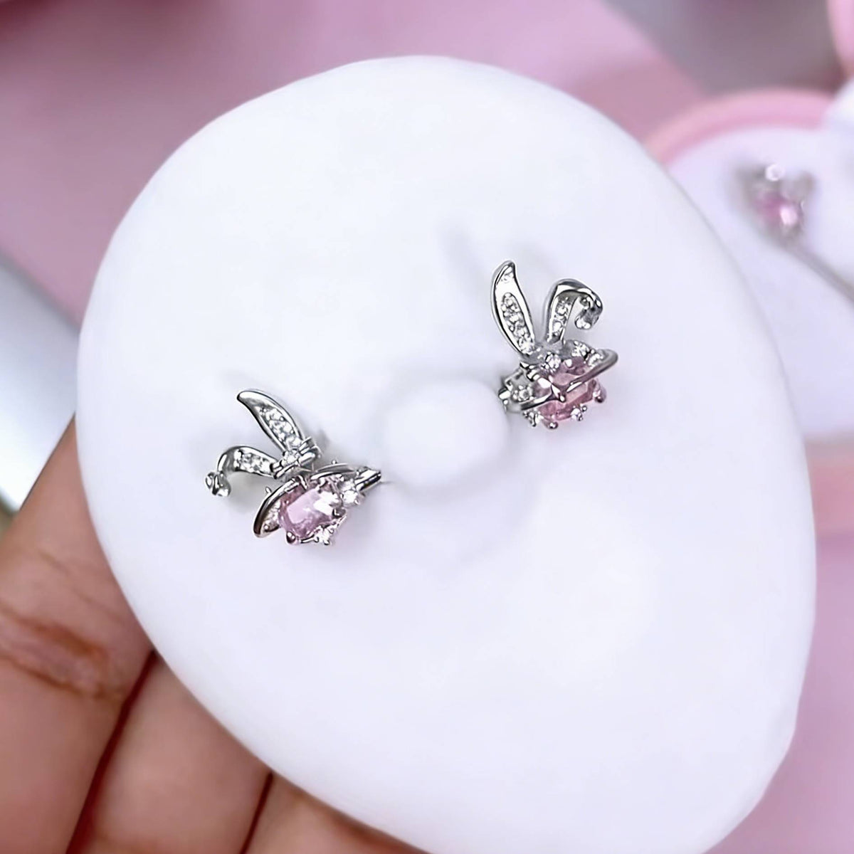 A pair of sparkling pink bunny ear nipple shields with heart stones shown on a silicone model.