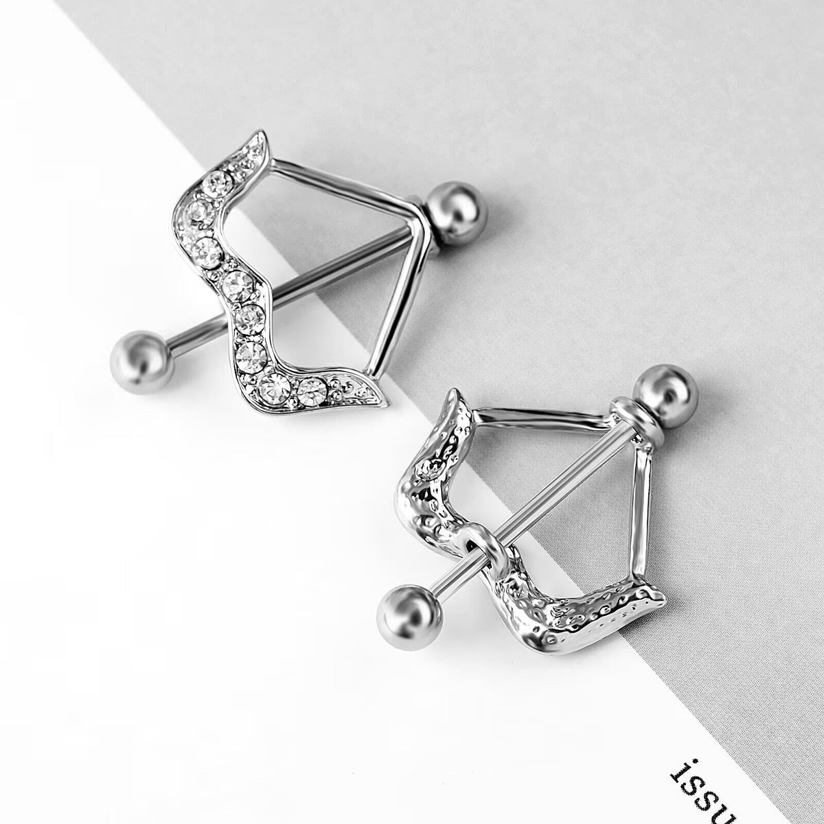 Aesthetic flat lay of bow-shaped nipple piercing jewelry on a minimalist background.