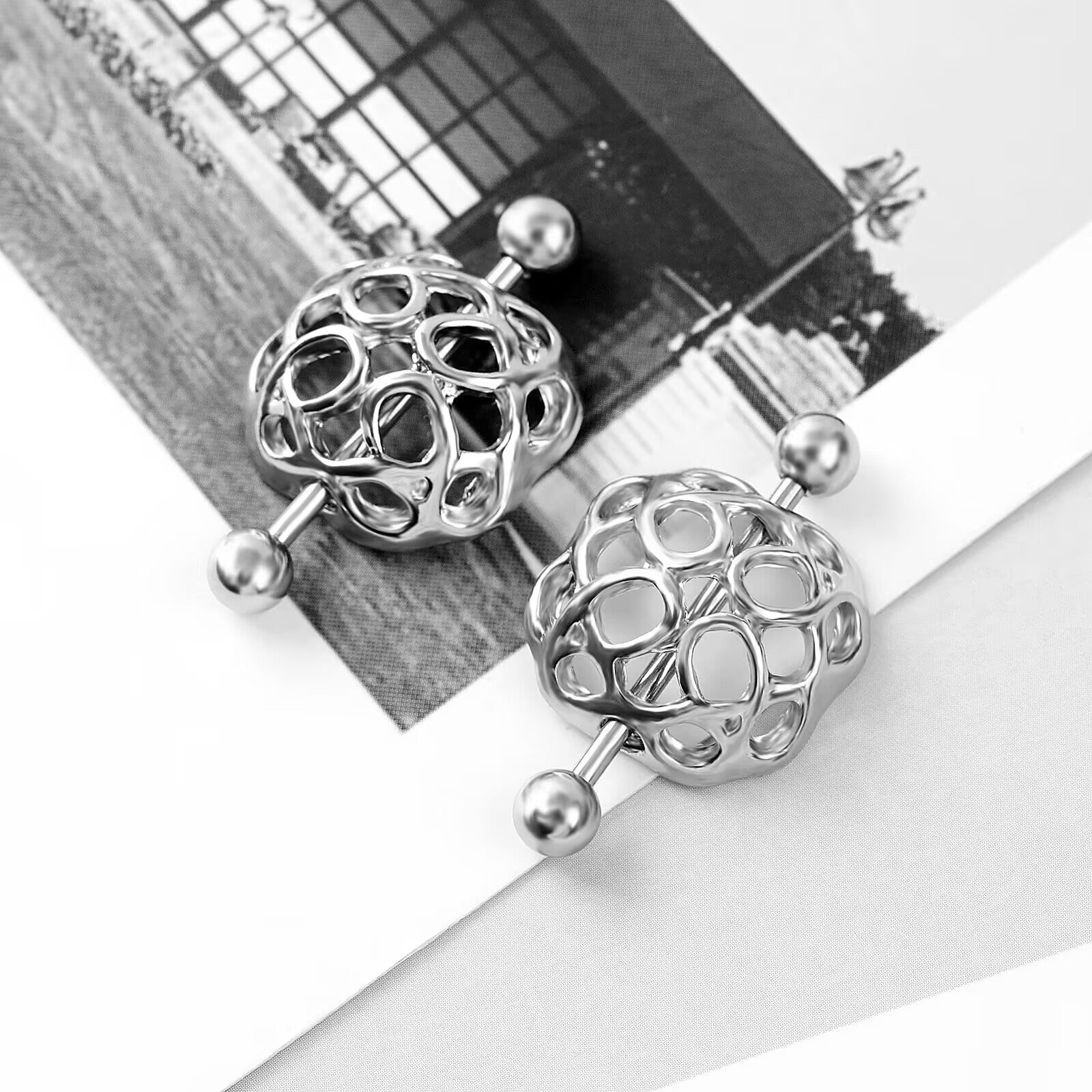 Lifestyle aesthetic shot of two geometric nipple shields on a minimalist magazine background.