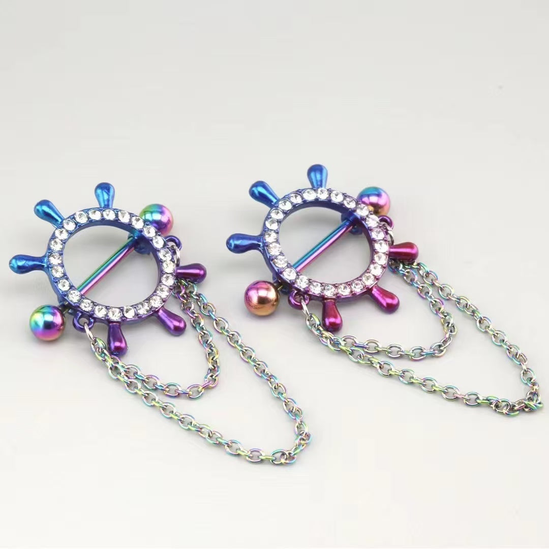 Close up shot of a pair of rainbow multicolor nautical themed nipple shields with clear CZ stones and multi-layered accent body chains under soft lighting.