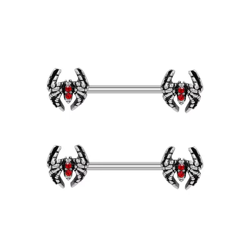 A pair of punk style spider nipple rings with vibrant red gem accents.