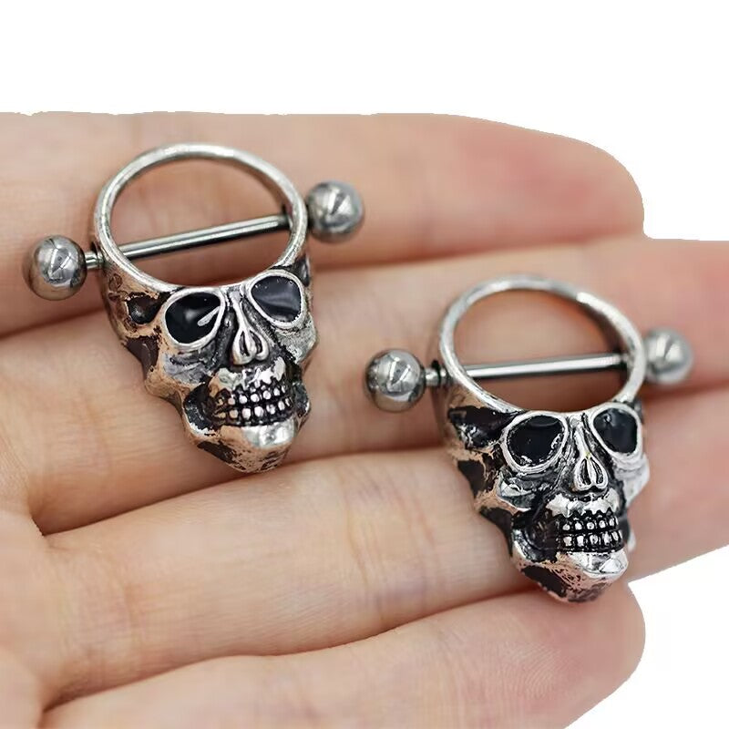 Close-up of two skull nipple shields held in hand to show realistic size and finish.