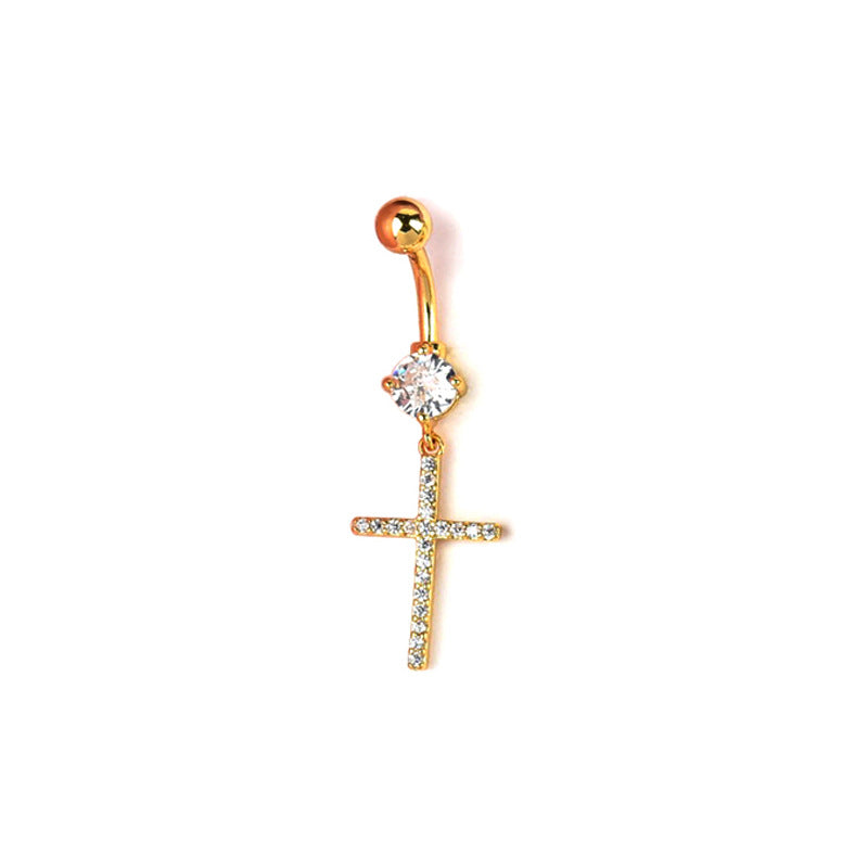 A gold-toned curved barbell belly button ring featuring a large clear solitaire crystal and a dangling cross fully paved with shimmering small stones, isolated on a white background
